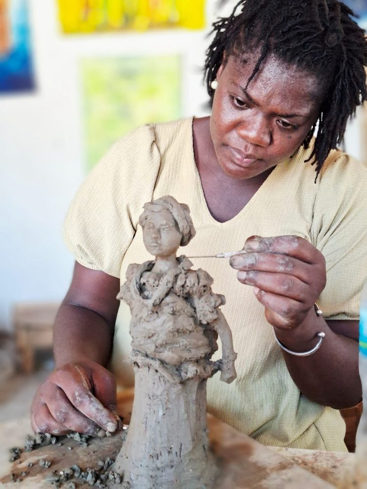A Gambian sculptor shaping a clay figure in her studio